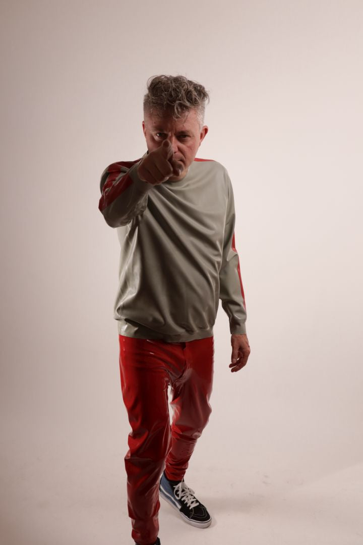 Fabian doing a 'we want you' imitation in his grey latex sweatshirt with red stripes on the arms, and red latex leggings and SK8 hi top Vans.