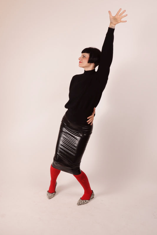 Our Model Anja von Abels striking a pose in our black latex pencil skirt. She is wearing it over a red pantyhose and combines it with a black wool turtleneck and leopard print ballerinas.