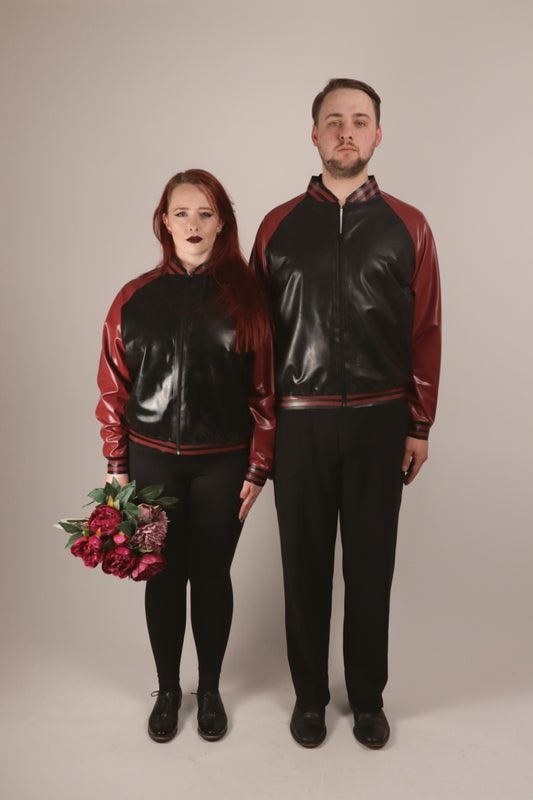 Total of Sarah and Paul standing attention in their matching black and bordeaux-red latex college jackets.