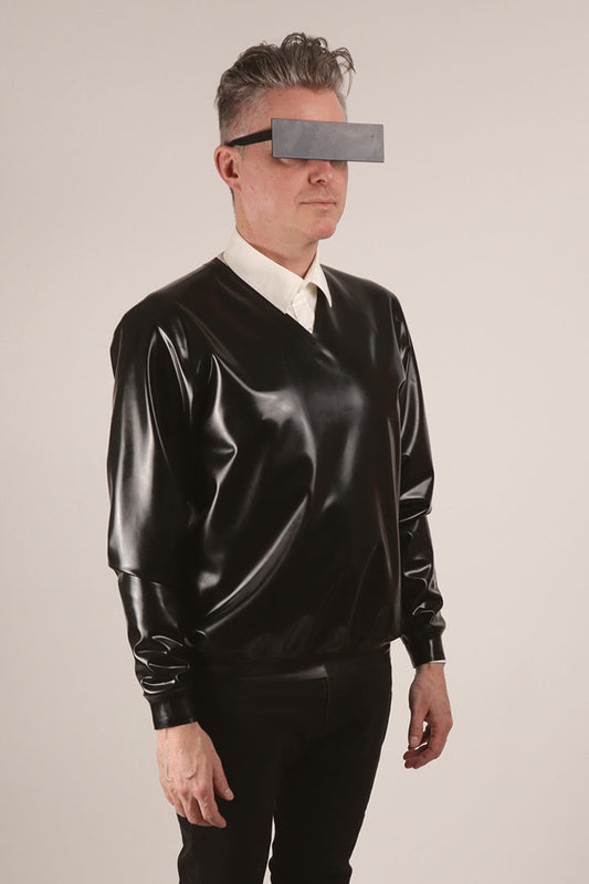 Close-up of Fabian wearing a black V-neck latex sweater over a white dress shirt .