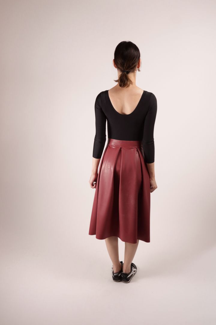 Rear view of our model Hani in our TARZA & JANE dark red kneelength latex pleat skirt