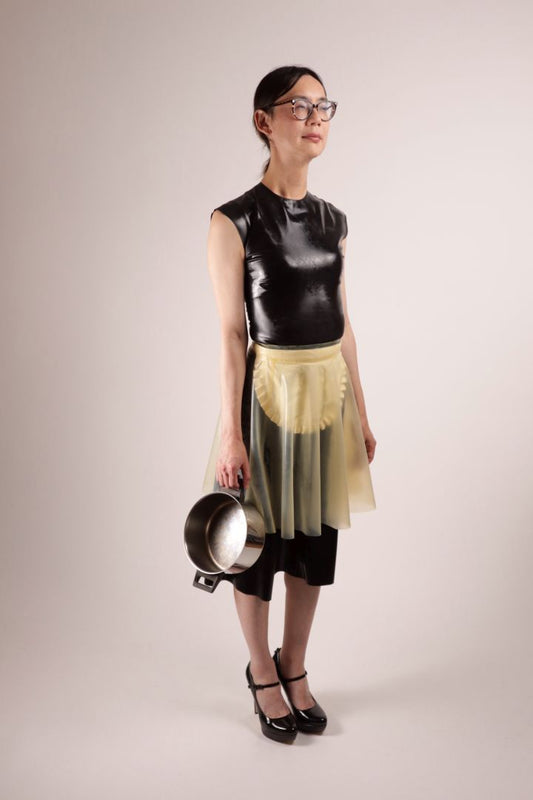 Our model Hani standing there quite bored in our TARZA & JANE impossible maid dress. it consists of a conservative black kneelength a-line dress with a t-shirt neck, plus a white maids apron under a transparent flared mini skirt. quite useless. also the empty pot dangling from Hanis right hand.
