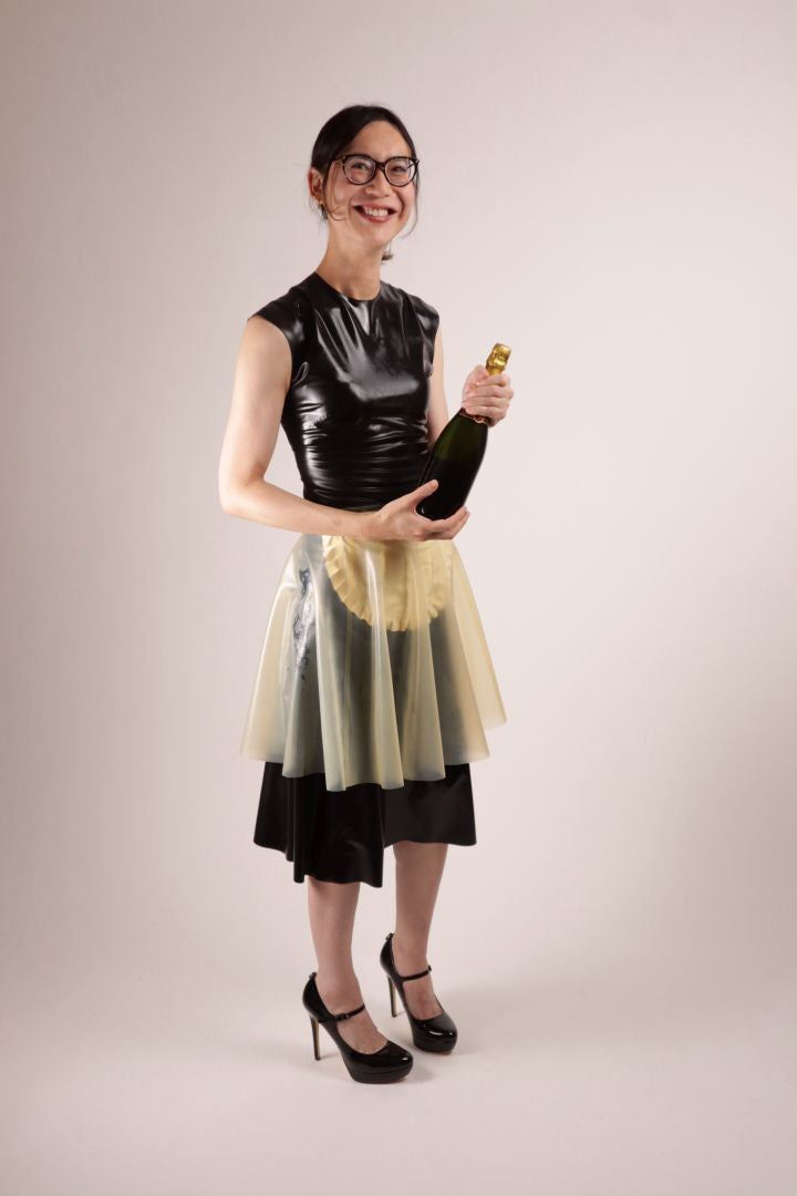 Hani grinning into the camera in our TARZA & JANE impossible latex maid dress. Classic 50s dress, apron, transparent flared latex skirt.