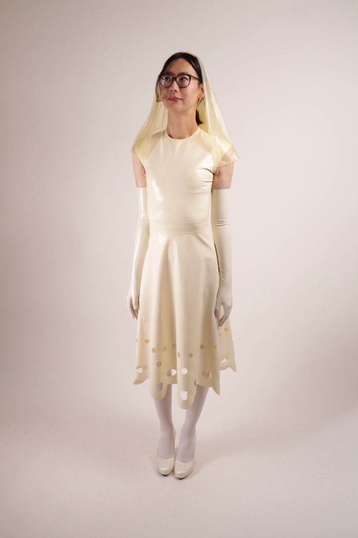 Hani posing in our TARZA & JANE lacey wedding dress. She has her latex veil pulled back.