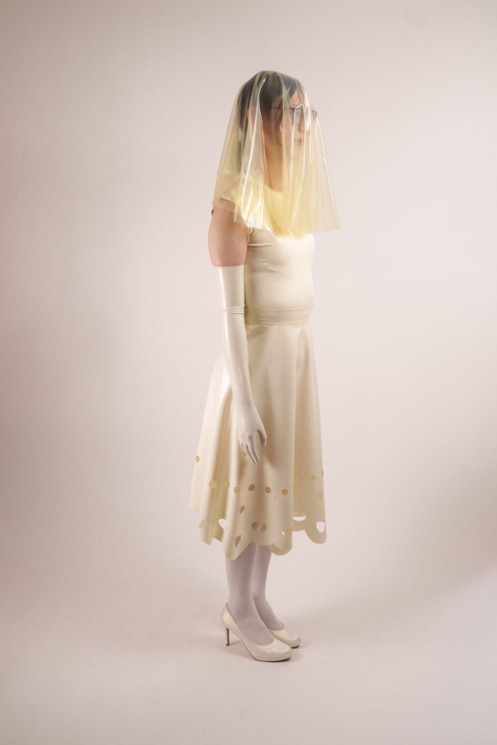 Side shot of Hani modelling our TARZA & JANE lacey wedding dress. Her face is hidden by her transparent latex veil.