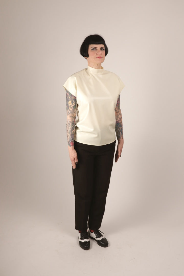 Our model Anja standing attention in her white loose sleeveless 60s latex top. The top is not tucked in.