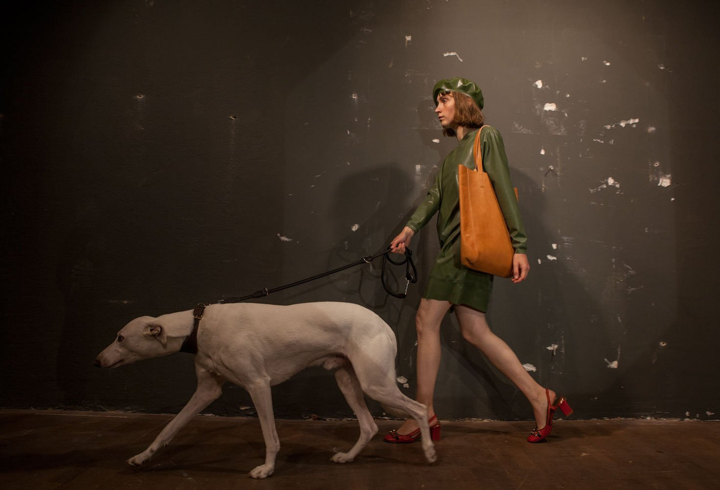 model walking her dog in an olive green latex sweatshirt dress and beret
