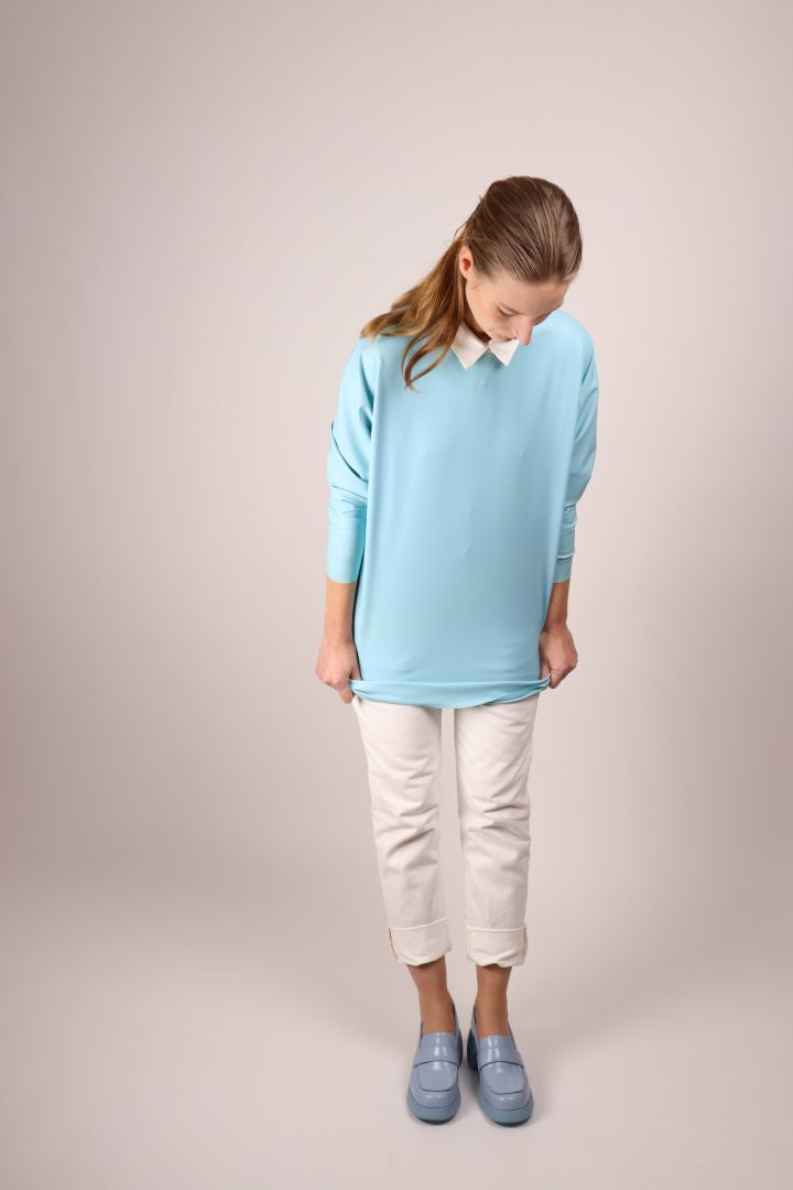 model in baby blue latex sweatshirt dress combined with white skinny jeans and a cotton dress shirt