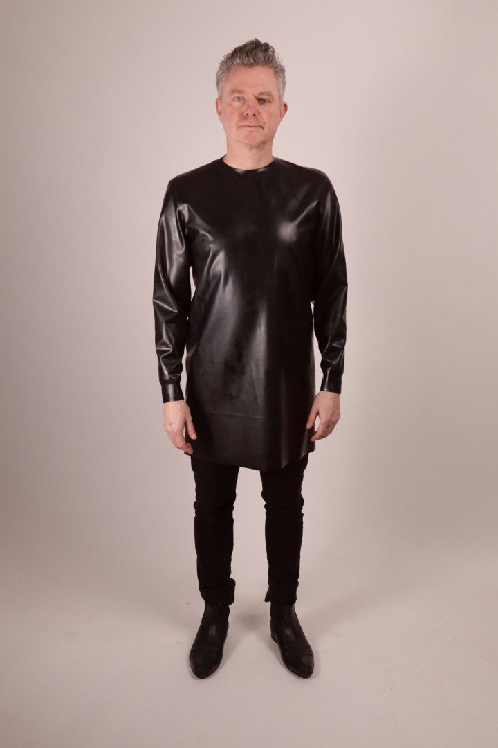a video of Fabian walking into focus wearing a black latex long sweatshirt over black skinny jeans and pointy black shoes.