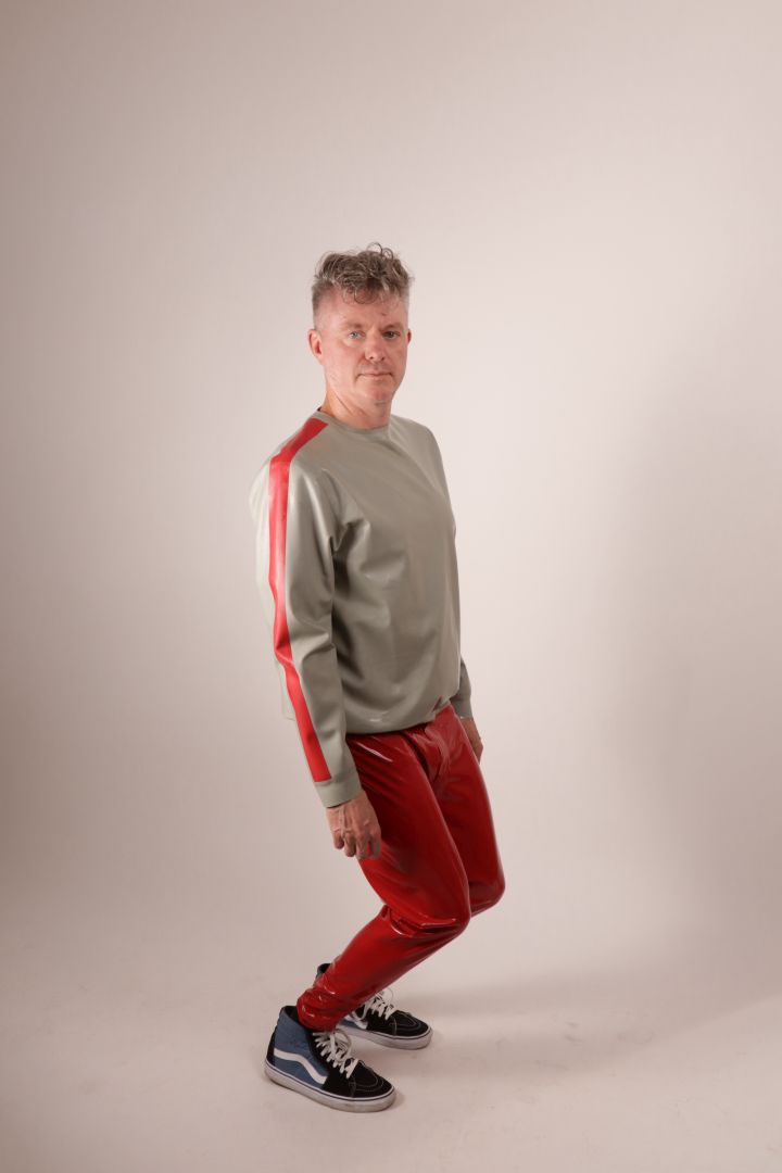 Fabian goofing around in his red latex loose leggings and his grey latex pullover with red stripes on the arms.