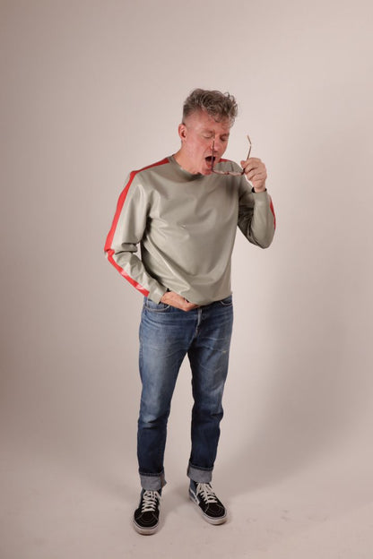 Fabian trying to clean his glasses in his grey latex sweatshirt with red stripes on the arms. 
