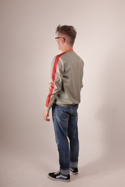 Half rear view of Fabian in his grey latex sweatshirt with red arm stripes, jeans and Vans.