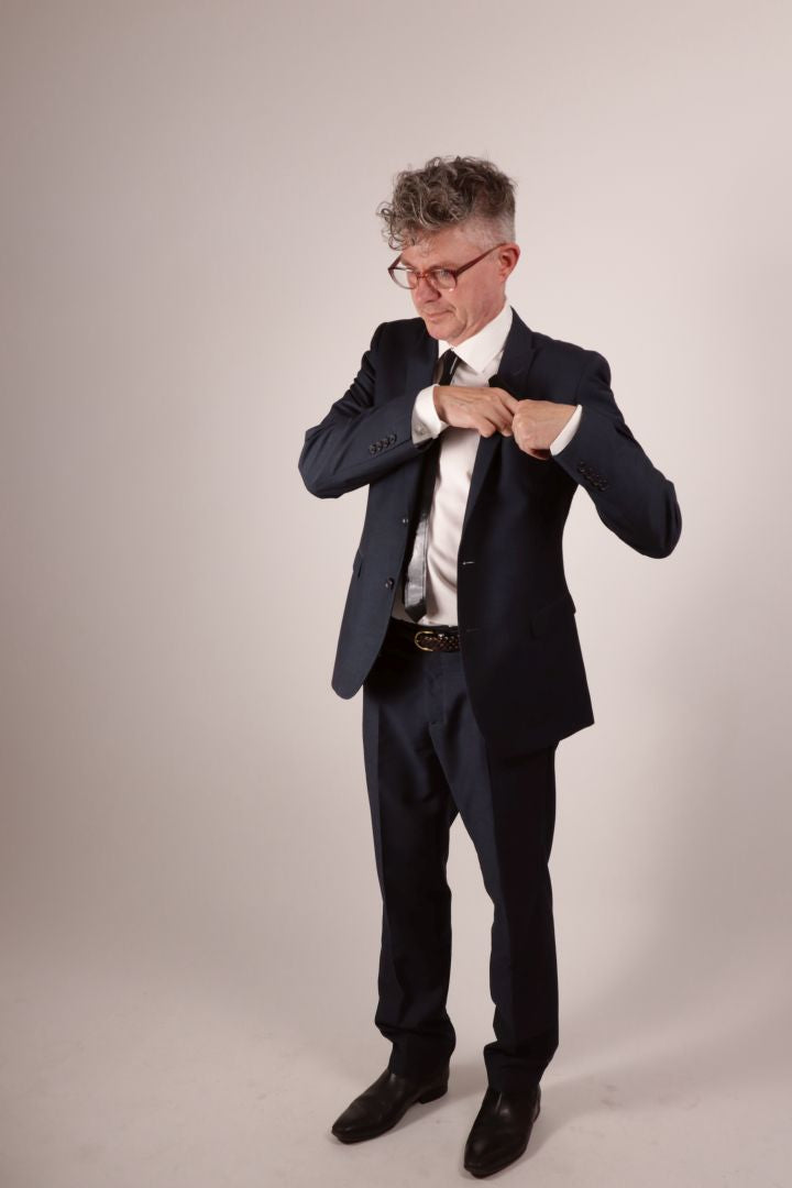 Our model Fabian tucking away his black latex pocket square after wiping his brow. He's wearing a navy blue business suit with a white dress shirt and his favorite new black latex tie. 
