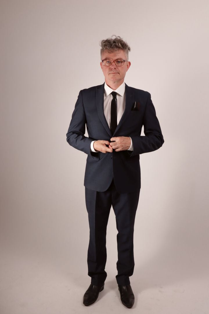 Our model Fabian buttoning his jacket. He's wearing a navy blue business suit with a white dress shirt and his favorite new black latex tie and matching pocket square. 