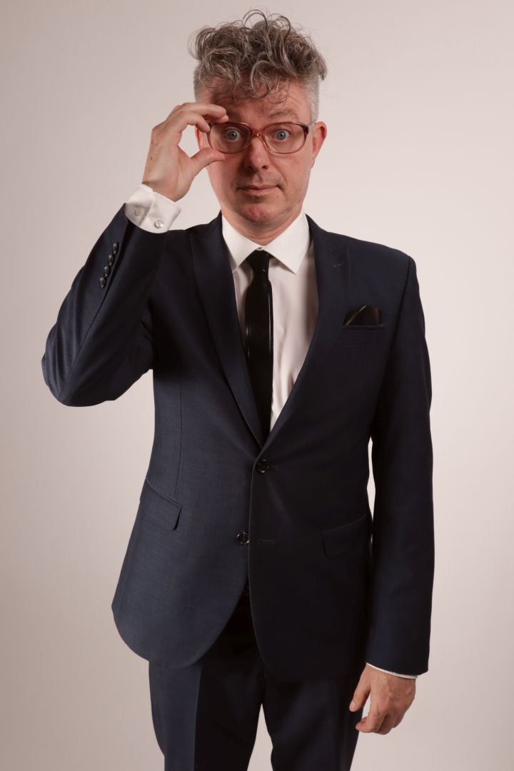 Fabian repositioning his glasses. He's in his navy blue business suit, white dress shirt and black narrow latex tie.