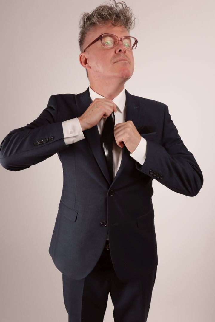 Fabian in his navy blue business suit and white dress shirt tightening his black narrow latex tie.