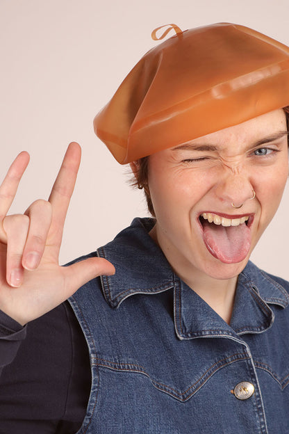 Annabel is wearing our transparent salmon latex beret and doing the devils horns sign with her fingers.