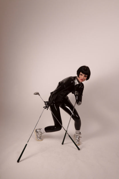 Our model Anja in a black latex catsuit, matching gloves, and a silver latex high shirt collar a bit like the ones Karl Lagerfeld used to wear. In this photo she's goofing around with three golf clubs simultaneously.