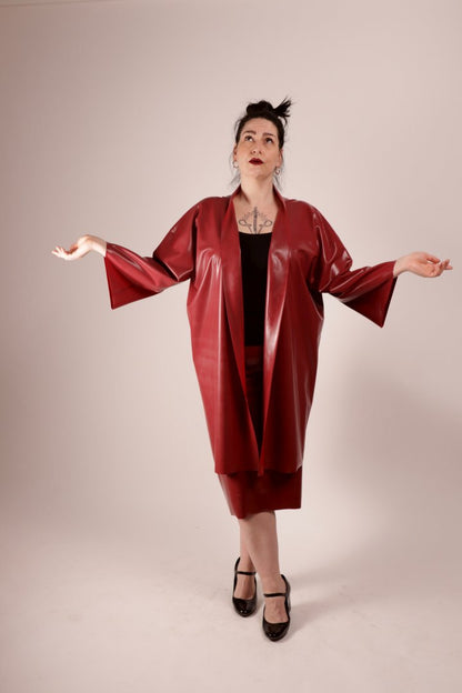 our model sadic sadie in our wine red latex fashion kimono and matching pencil skirt, with her arms lifted a quarter and her eyes looking up to the sky