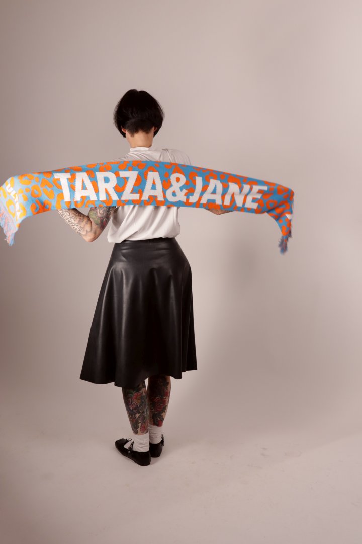 A back of model Anja stretching our knit acrylic ultra fan scarf behind her back so you can see the knit design.