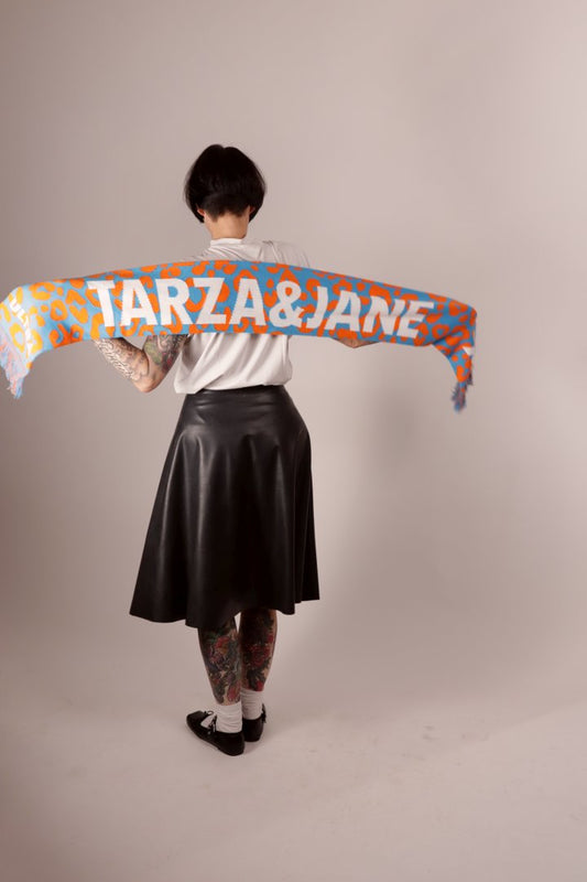 A back of model Anja stretching our knit acrylic ultra fan scarf behind her back so you can see the knit design.