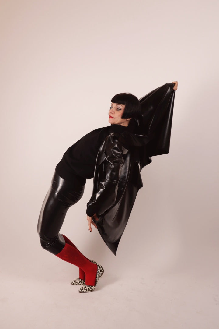 Our Model Anja von Abels flexing backwards in our black latex pencil skirt and matching latex cocoon coat. She is wearing it over a red pantyhose and combines it with a black wool turtleneck and leopard print ballerinas.