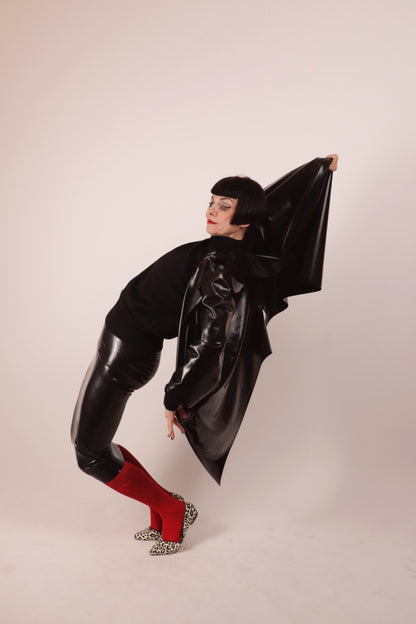 Our Model Anja von Abels flexing backwards in our black latex pencil skirt and matching latex cocoon coat. She is wearing it over a red pantyhose and combines it with a black wool turtleneck and leopard print ballerinas.