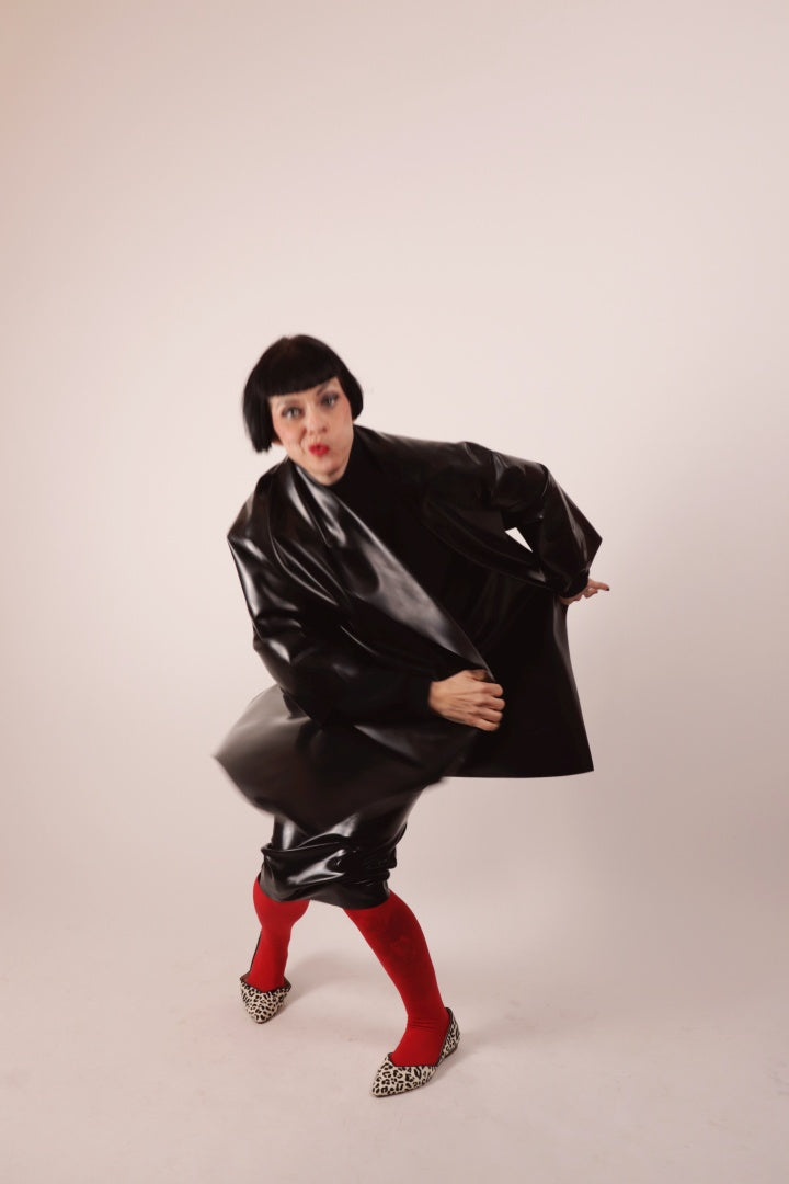 Our Model Anja von Abels twirling in our black latex pencil skirt and matching latex cocoon coat. She is wearing it over a red pantyhose and combines it with a black wool turtleneck and leopard print ballerinas.