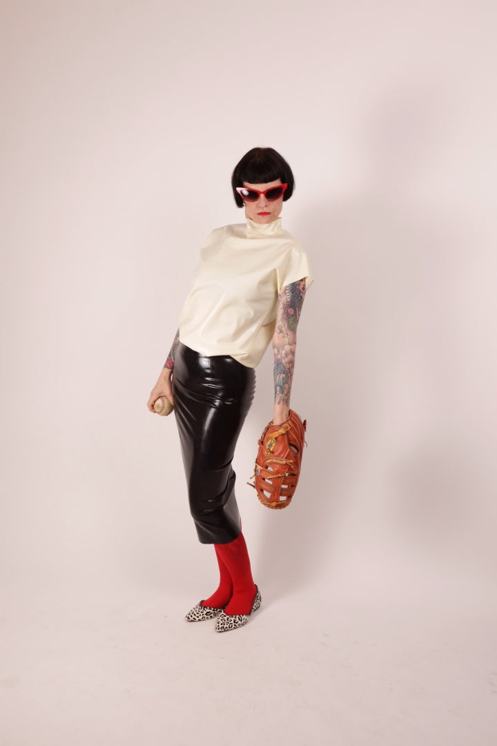 Our model Anja in our black latex pencil skirt and white latex loose 60s sleeveless top. She combines it with a red pantyhose and leopard ballerinas, a baseball and a matching baseball glove, plus red butterfly sunglasses.