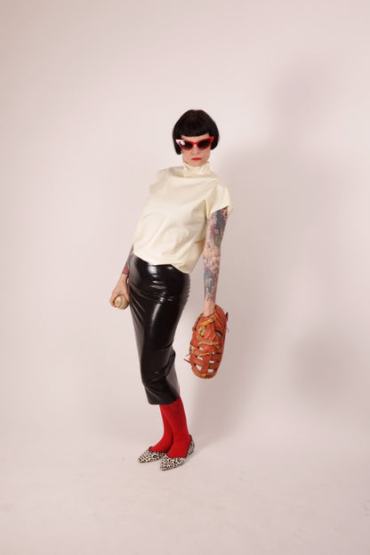 Our model Anja in our black latex pencil skirt and white latex loose 60s sleeveless top. She combines it with a red pantyhose and leopard ballerinas, a baseball and a matching baseball glove, plus red butterfly sunglasses.
