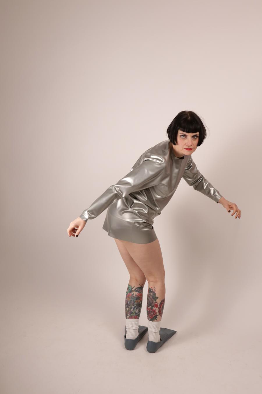 model Anja Abels in silver latex sweatshirt dress twisting towards camera