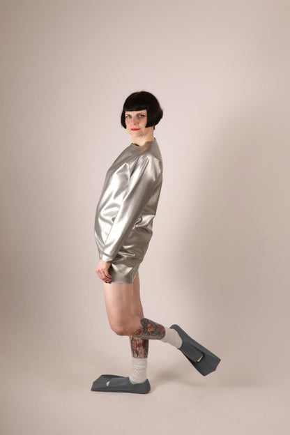 model Anja Abels in silver sweatshirt dress and tennis socks and fins posing, side view