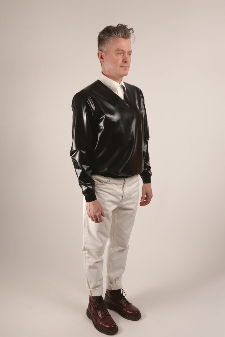 Fabian wearing his black V-neck latex sweater over a white dress shirt and with white skinny jeans and cherry red Dr. Martens boots.