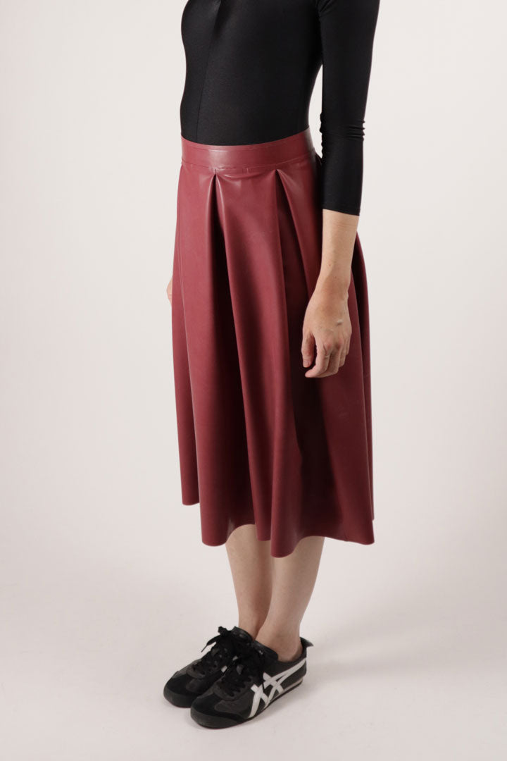 Model Hani in a dark or bordeaux red latex pleat skirt
