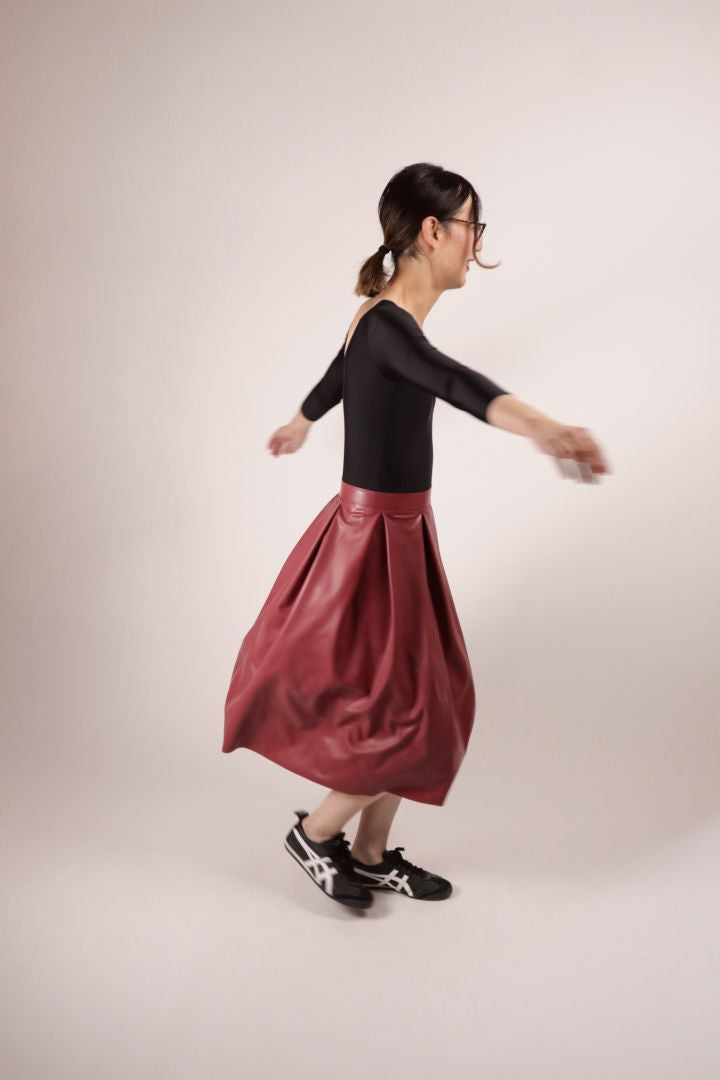 Model Hani spinning her bordeaux red kneelength latex pleat skirt