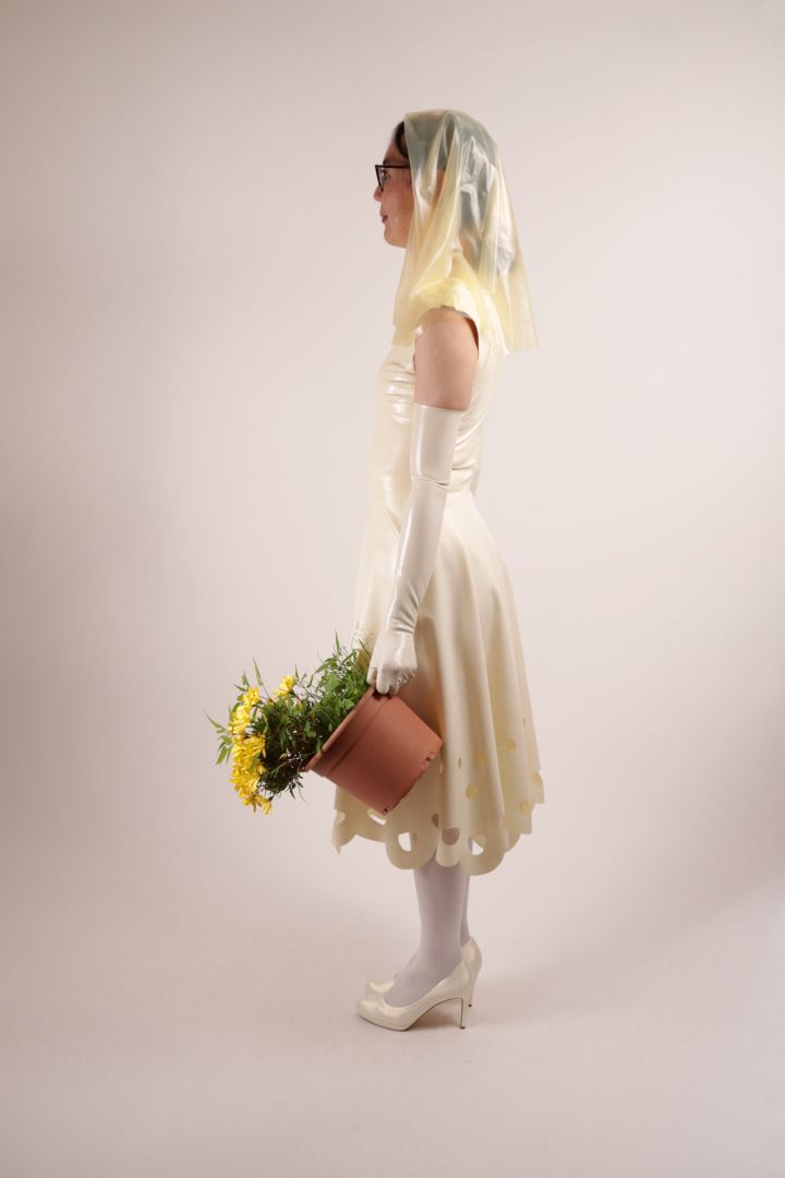 Side shot of Hani modelling our TARZA & JANE lacey wedding dress. Her face is hidden by her transparent latex veil. Meditating before throwing the flower pot over her shoulder. Catch!
