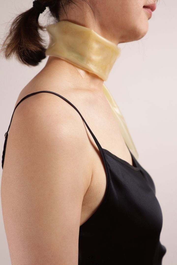 Close-up of Hani wearing the  transparent latex scarf around her neck. Seen from the right.