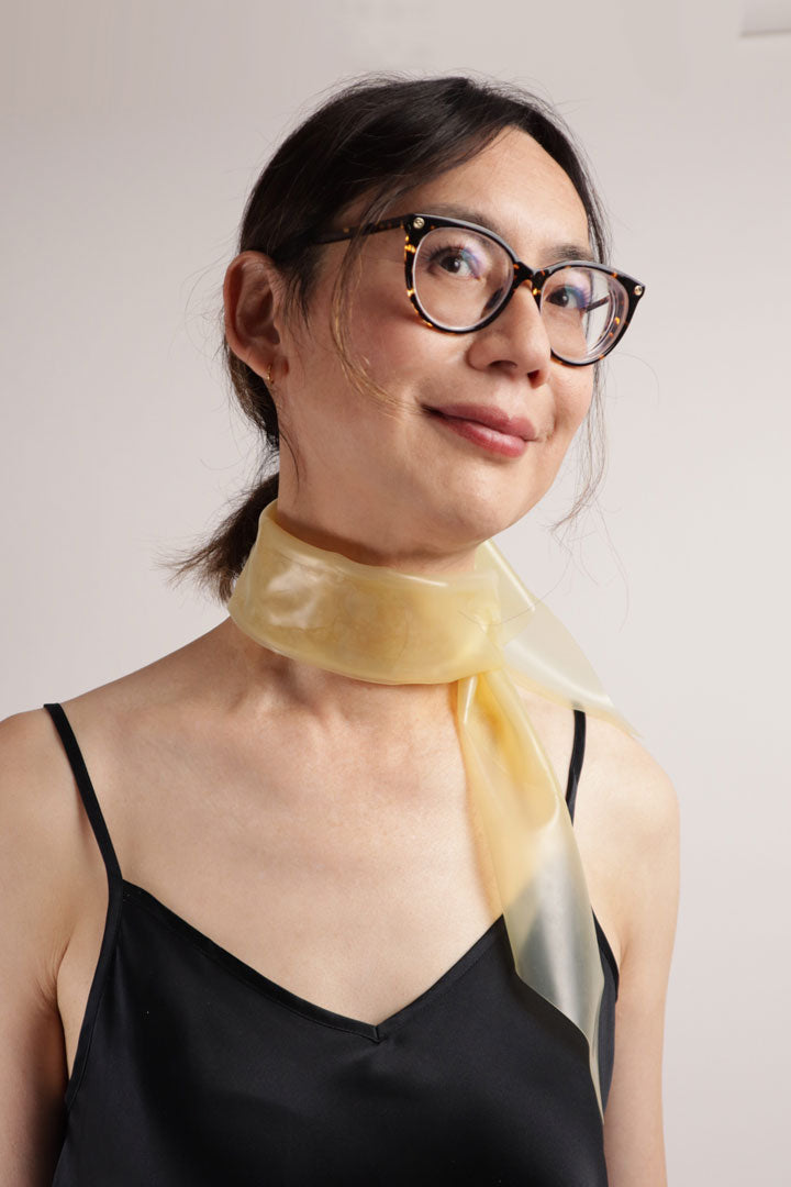 Hani modelling our TARZA & JANE latex scarf. She sports the transparent version as her latex fashion key-piece. She wears it with the knot on the side like a chic fashionable stewardess would.