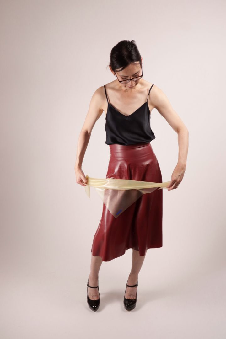 Our model Hani rolling the TARZA & JANE transparent latex scarf triangle into a neck scarf.