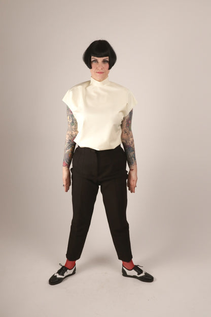 Our model Anja standing attention in her white loose sleeveless 60s latex top tucked-in and two-tone brogues.