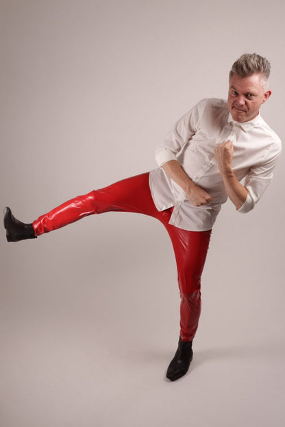 Fabian in shiny red TARZA & JANE mens loose latex leggings and a white dress shirt doing a carate move
