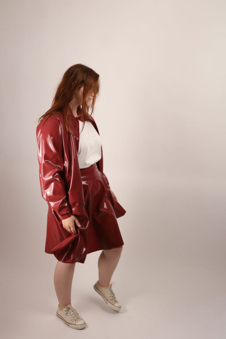 woman in bordeaux red harrington latex jacket and skating skirt