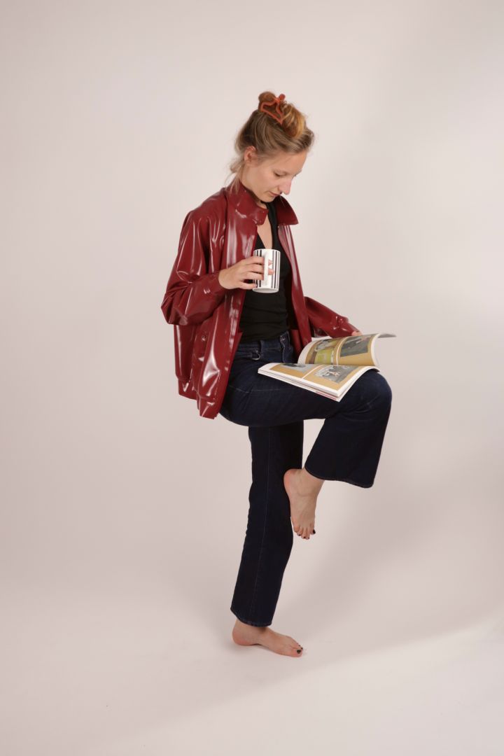 model reading a magazine in dark red latex harrington jacket