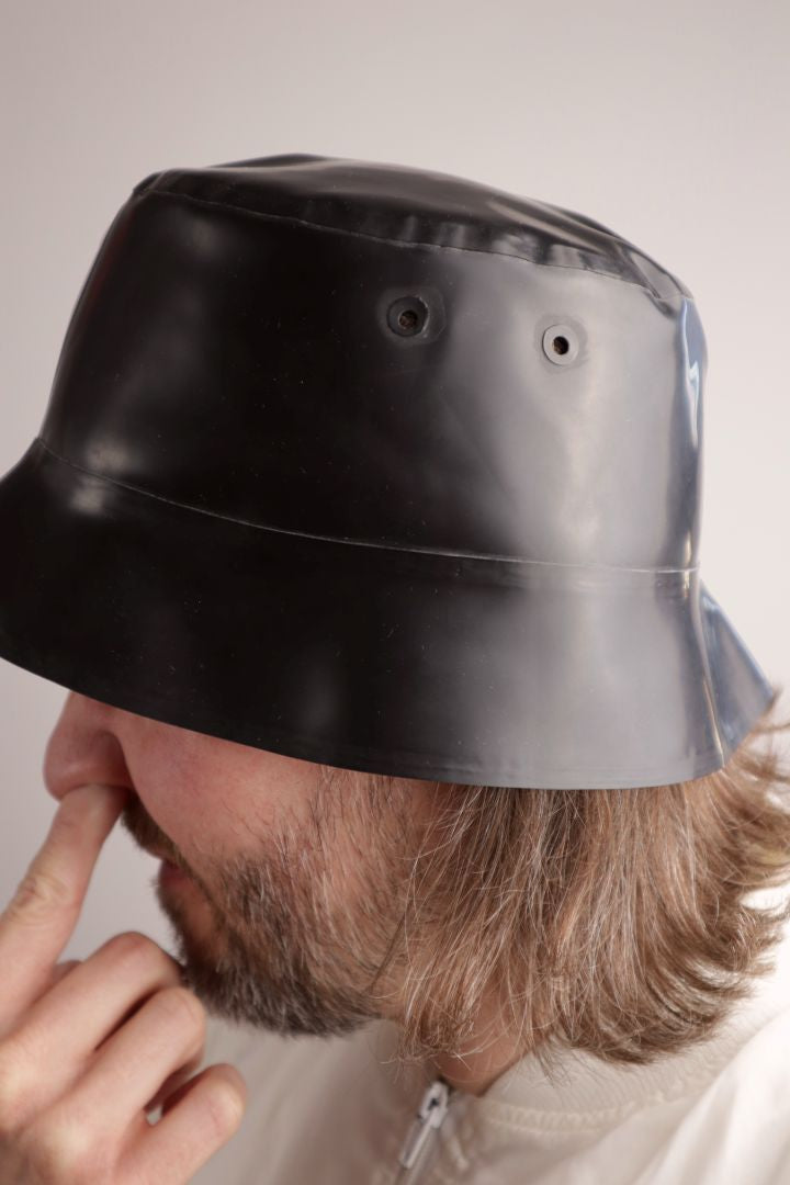 model-picking-his-nose-under-black-latex-bucket-hat