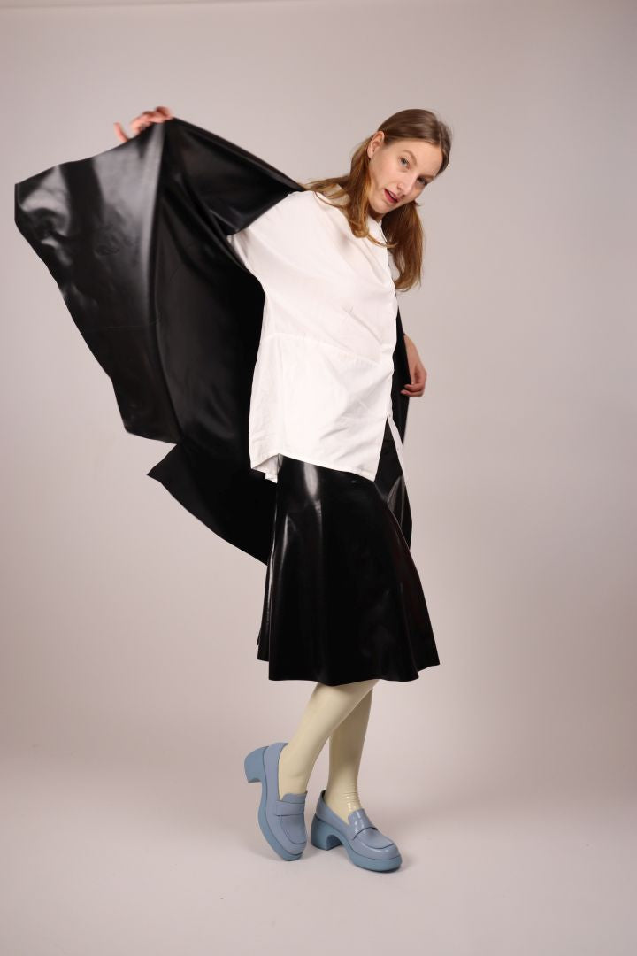 model-putting-on-black-latex-trench-coat-over-midi-skirt